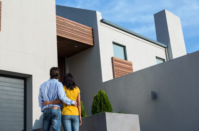 Happy Hispanic couple standing and looking at the new house Happy Hispanic couple standing and looking at the new house