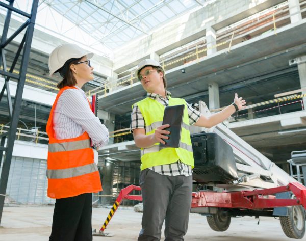 Team of builders of engineers working on a construction site Man engineer and woman architect at a construction site. Building, development, teamwork and people concept.