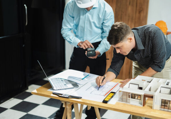 Architect caucasian man working, blueprint meeting for project working with partner on model building at company office.
