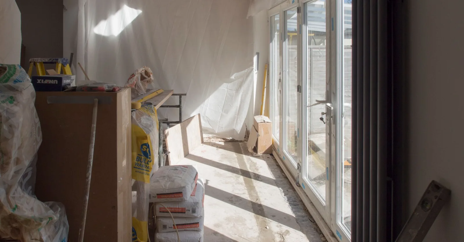 A construction area featuring renovation work in progress with large windows bringing in natural light